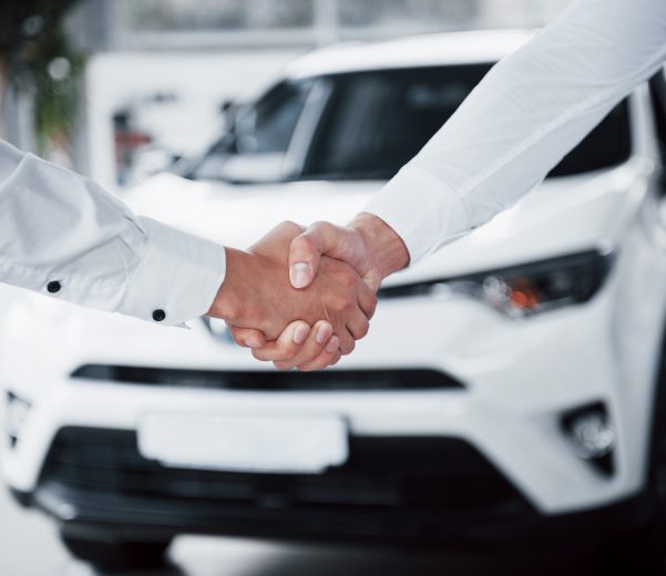 Close up of sales manager in black suit selling the car to the customer.